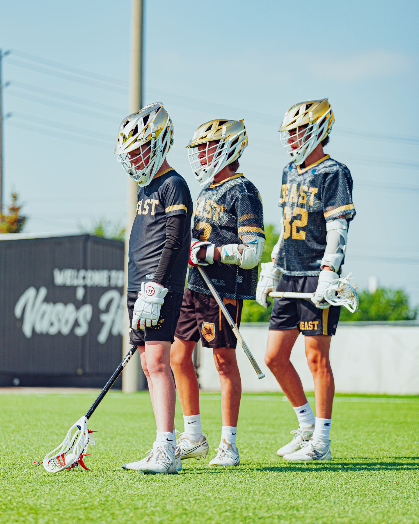 Three BEAST players in gold helmets and black-and-gold mesh jerseys at Vaso's Field