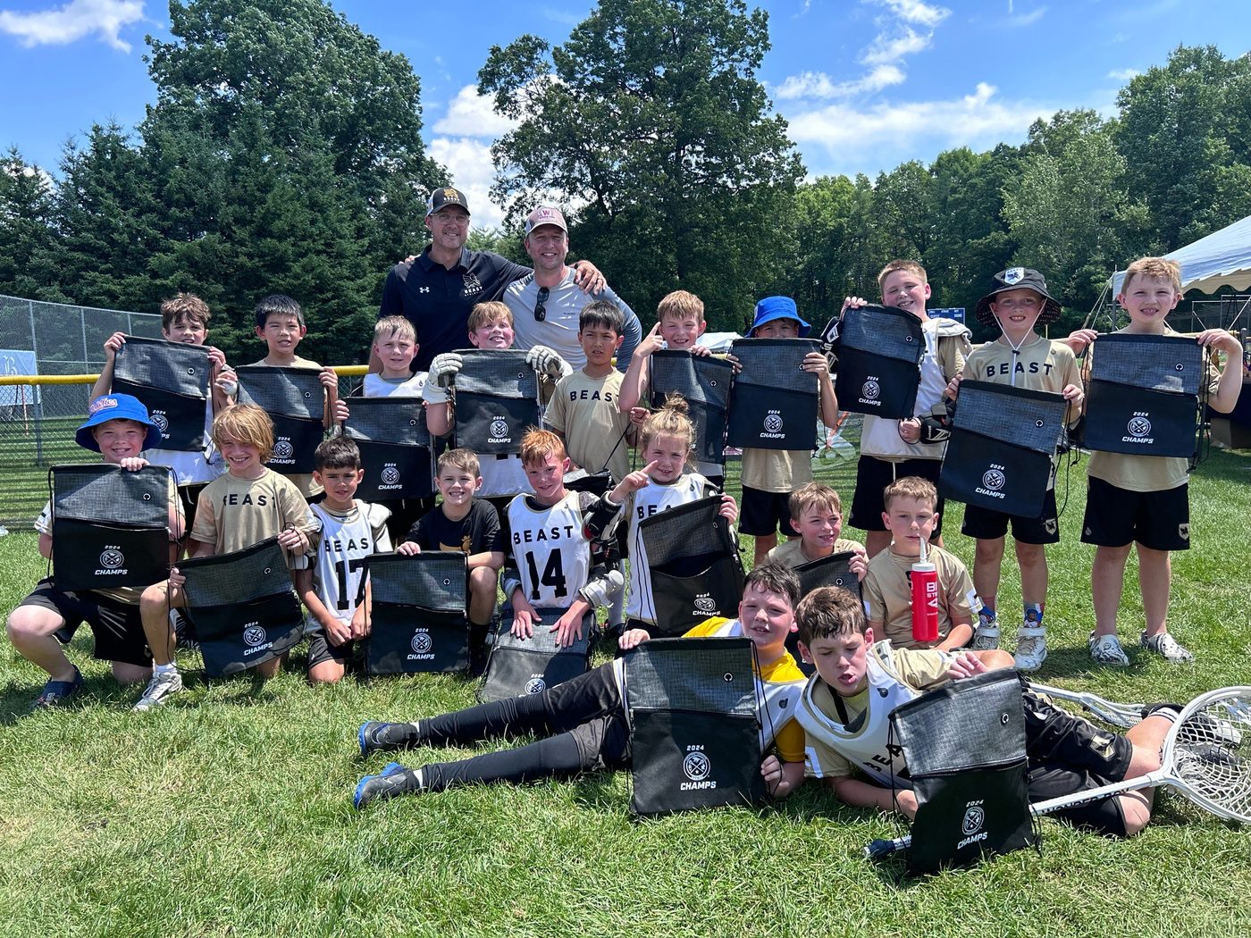 A young BEAST team and two coaches holding up 2024 Champs bags