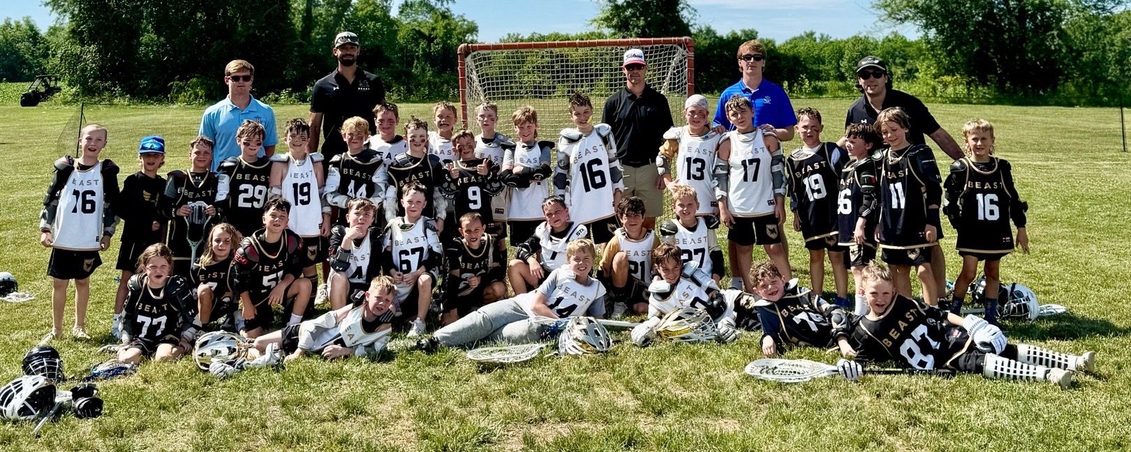 Two BEAST teams, one in white and one in black, together with their coaches in front of a goal